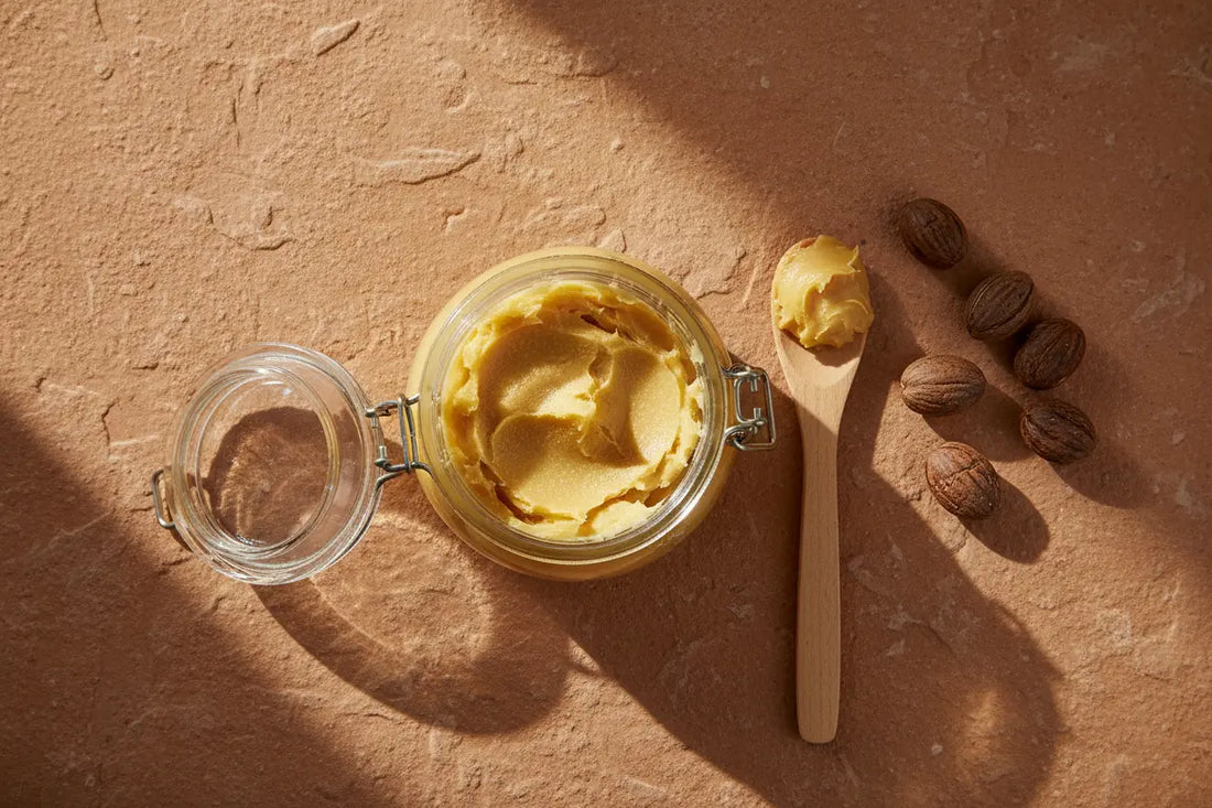 Pure unrefined raw shea butter displayed in a glass jar to showcase its golden-yellow color and ethical origin
